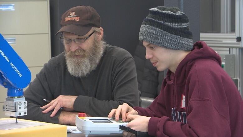 A father and son are pictured using a 3D printer.