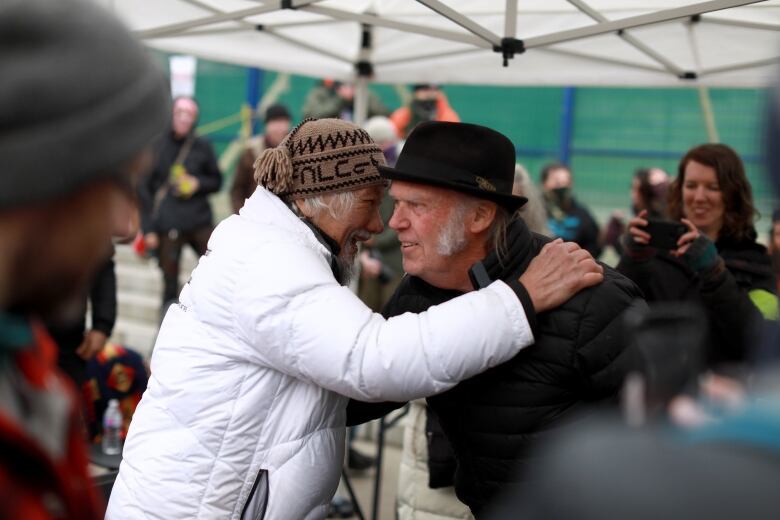 David Suzuki is pictured speaking closely to Neil Young on stage. 