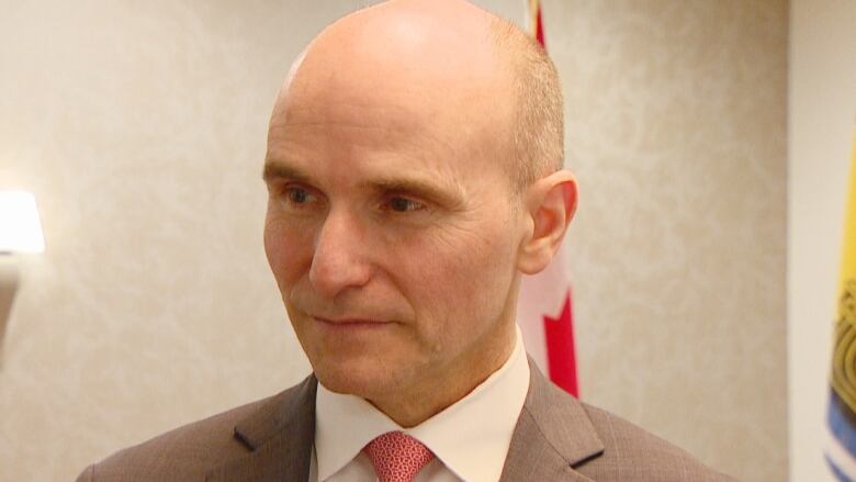  A man in a grey suit with a white shirt and a red tie.