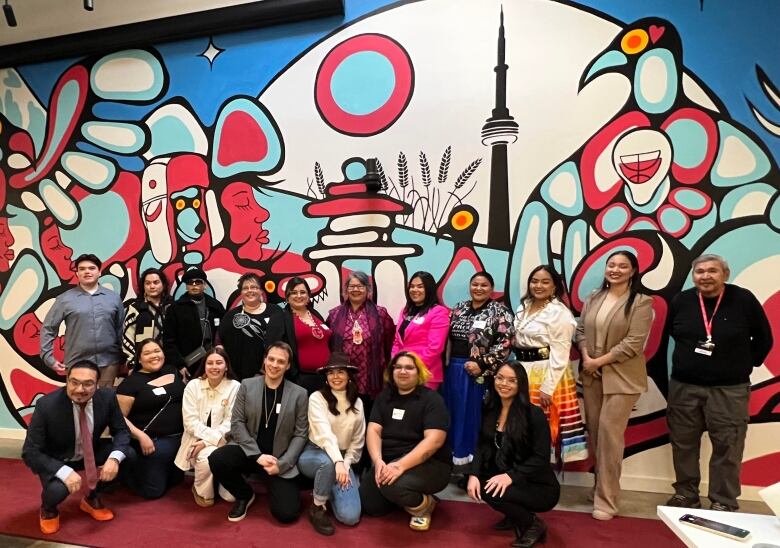 A group of people in front of a indoor mural of Toronto.