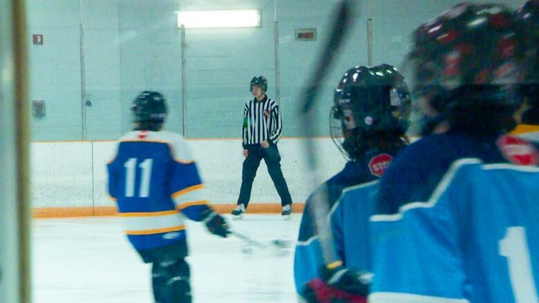 A teenager with a black and white striped referees shirt is seen skating.