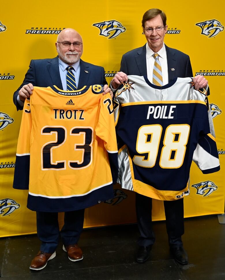 Former Nashville Predators head coach Barry Trotz, left, and general manager David Poile, pose for a photograph while holding up jerseys after a news conference.