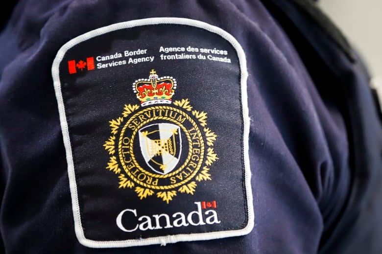 A person wears a Canada Border Services Agency badge shown on one shoulder.