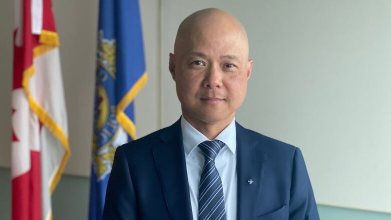 A man in a suit standing in front of flags.