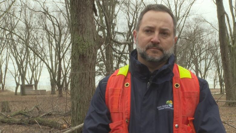 A man stands in front of trees. 