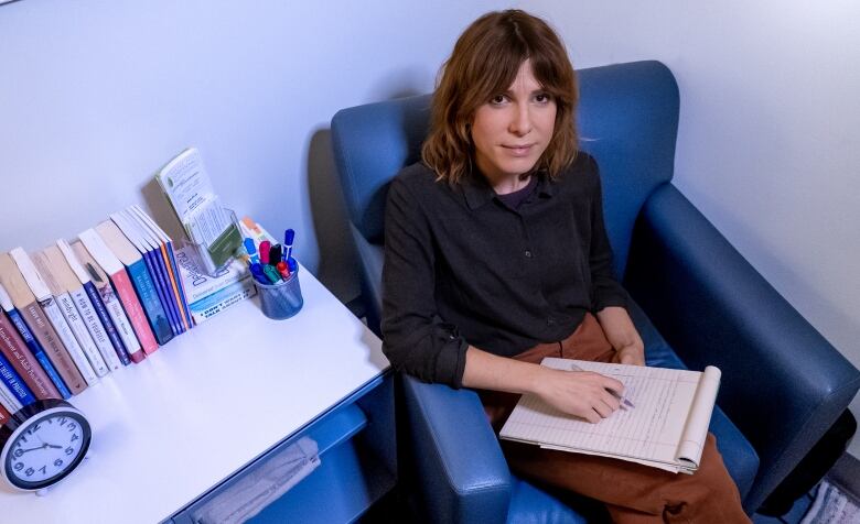 Photo of Kelsey White sitting in a chair in her office.  