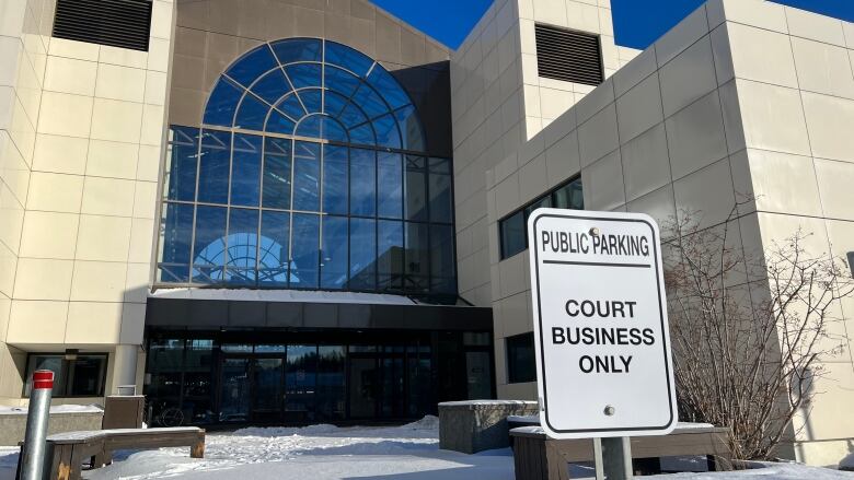 A sign reading, 'Public parking, court business only,' is seen in front of a large institutional building.