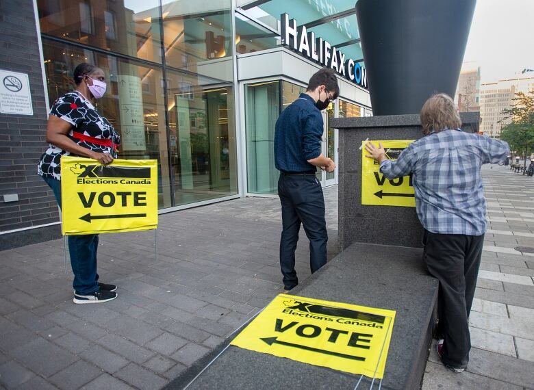 Elections Canada workers place signage at the Halifax Convention Centre as they prepare for the polls to open in the federal election in Halifax on Monday, Sept. 20, 2021.