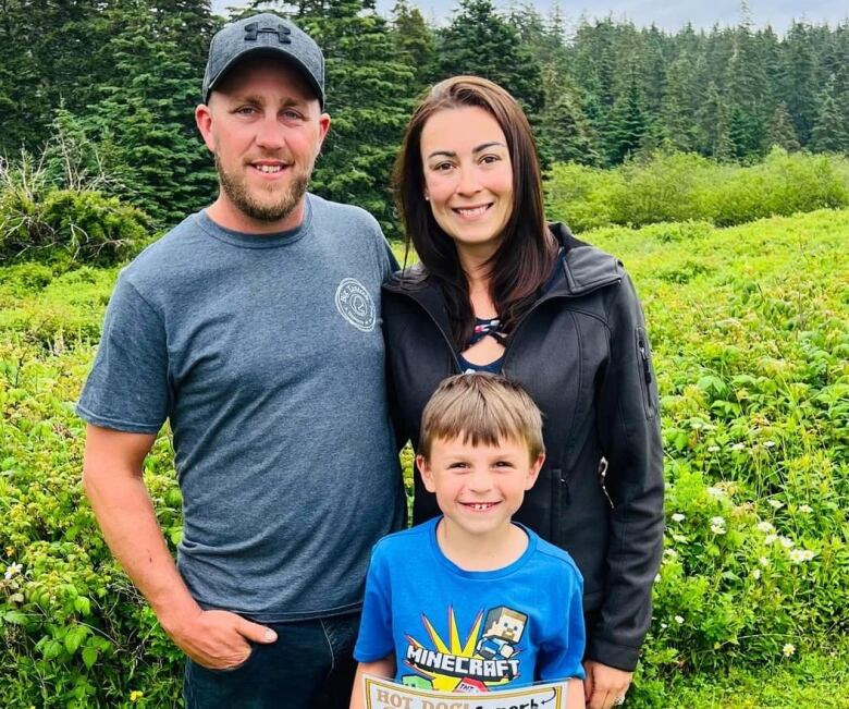 Two parents stand outside with their young son in the middle