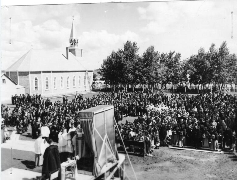 A black and white photo shows a large crowd on the grounds of the old boarding school in le--la-Crosse.