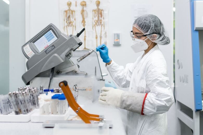 A scientist in protective equipment works at DNA testing.