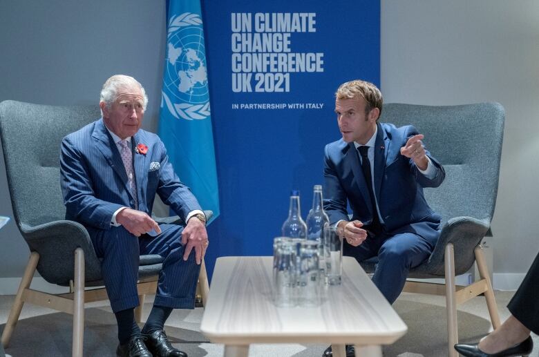 Prince Charles and French President Emmanuel Macron sitting down and speaking at the COP26 summit. 