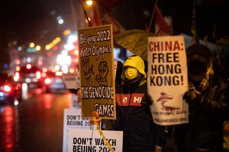 People hold signs during a protest against the Beijing Winter Olympics outside the Chinese Consulate in Vancouver.