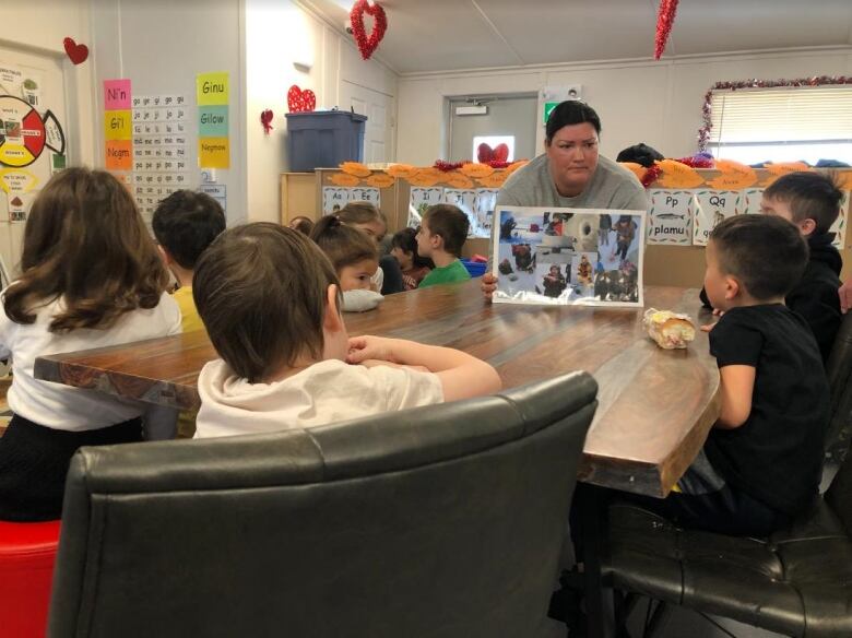 Brenda Germain sits at one end of the table, showing photos to her students.