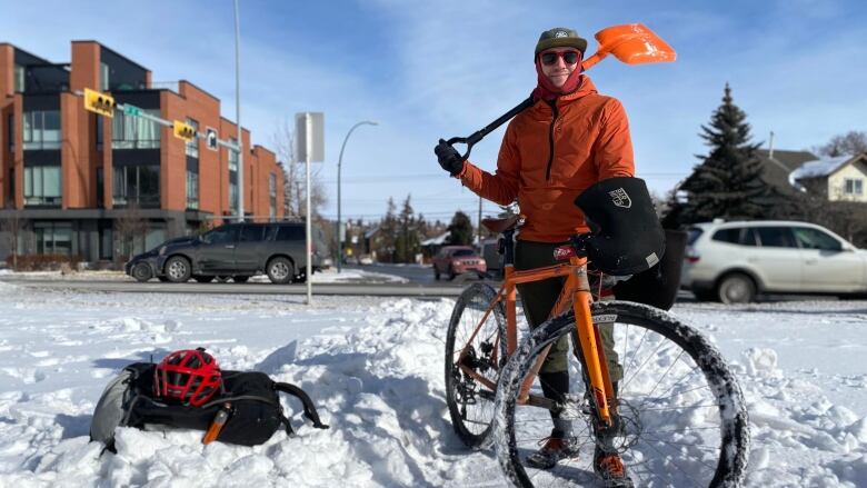 A man stands with his bike and a shovel.