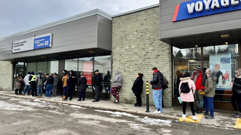 More than a dozen people lined up outside an SAAQ office. 