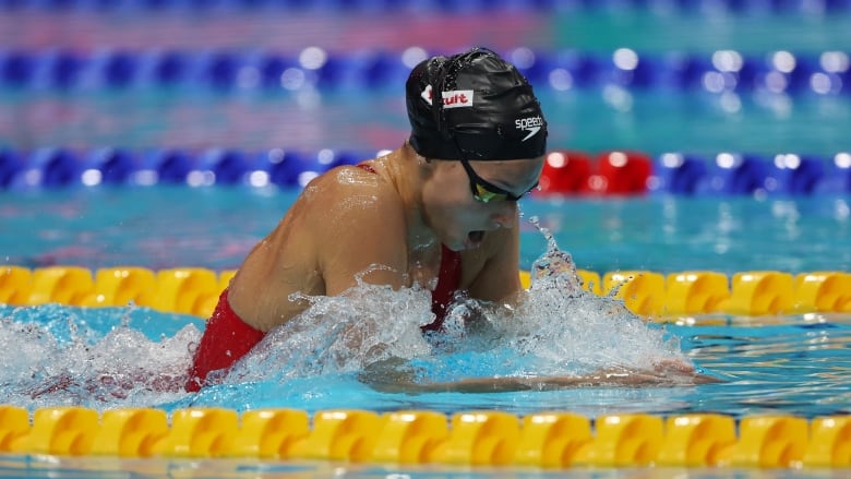 Summer McIntosh swims the butterfly wearing a red swimsuit, goggles and a black swim cap.