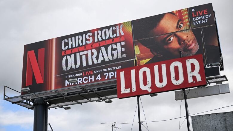 A billboard with the a headshot of a serious-looking man includes the Netflix logo and text that says, 