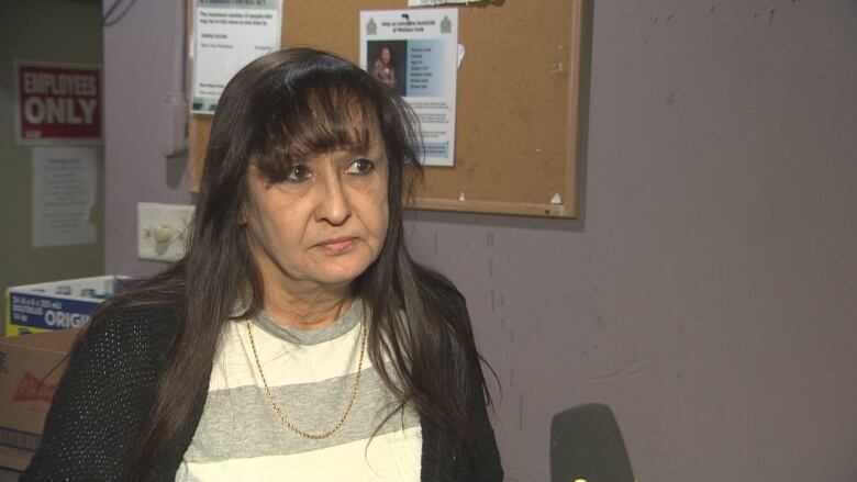 A woman with a gold necklace and bangs looks forward.