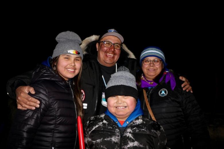 A family of four smiles at the camera.