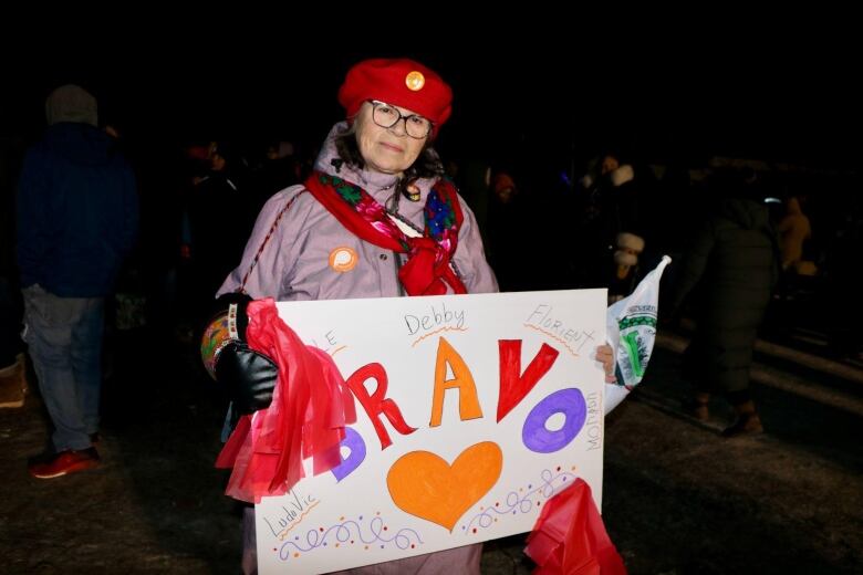 A woman stands with a signs reading 'bravo'.