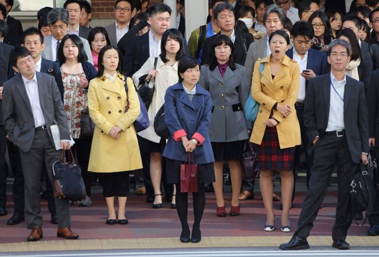 A bunch of people stand on the street.