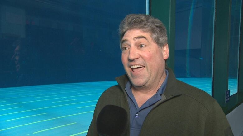 A man smiles in front of a large tank of water.