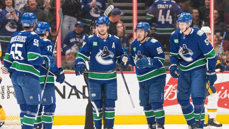 Vancouver Canucks' Elias Pettersson, centre, is congratulated by teammates after scoring a goal against the Nashville Predators during first period NHL hockey action.