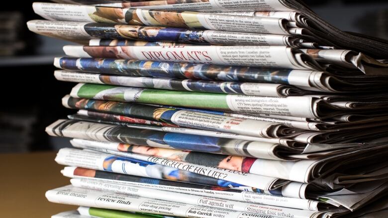 Stack of newspapers on a desk.