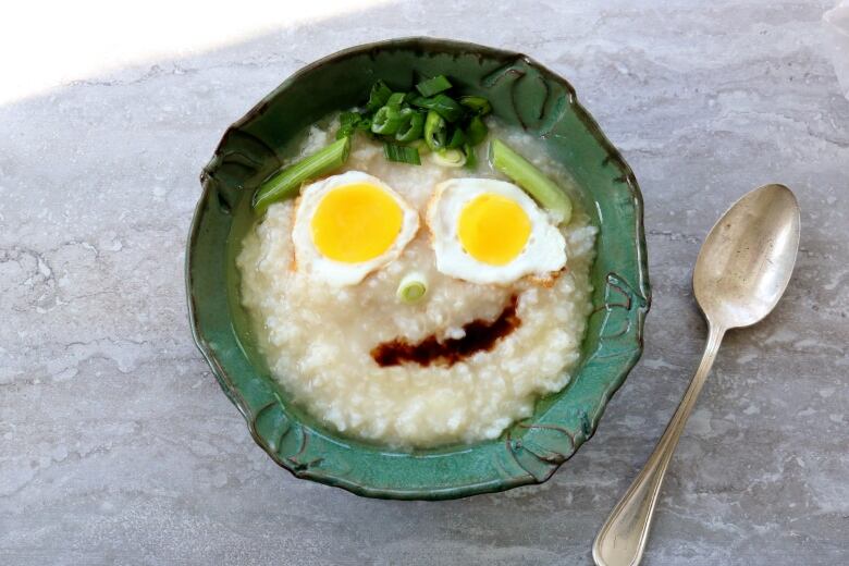 Porridge with a smiley face made of eggs, soy sauce and green onions.