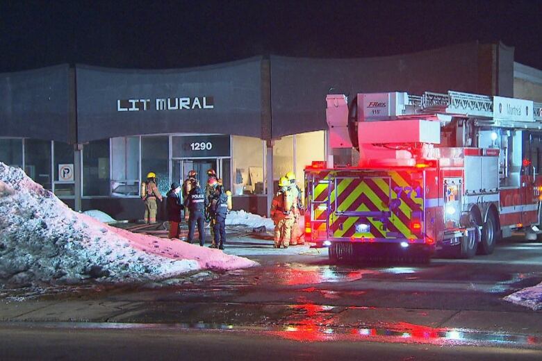 firefighters, firetrucks and police officers in front of commercial building