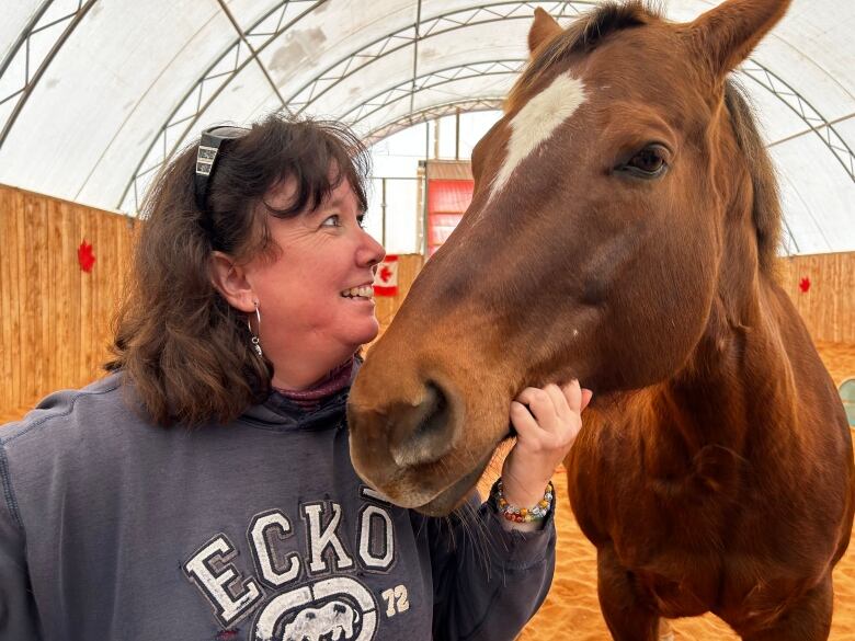 A woman smiles at her horse.