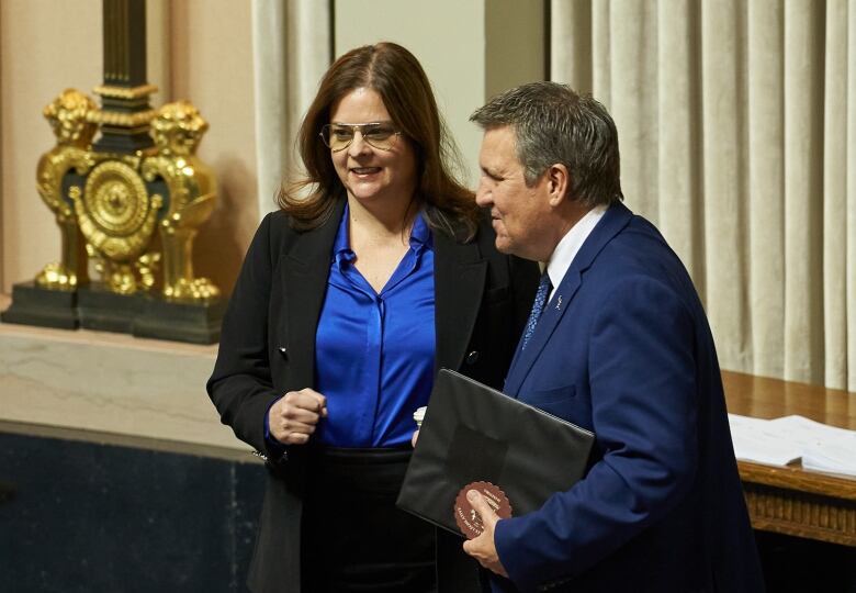 Manitoba Premier Heather Stefanson and Finance Minister Cliff Cullen stand beside each other and have a conversation in the legislative chamber before Cullen walks to his seat and prepares to read the 2023 budget speech.