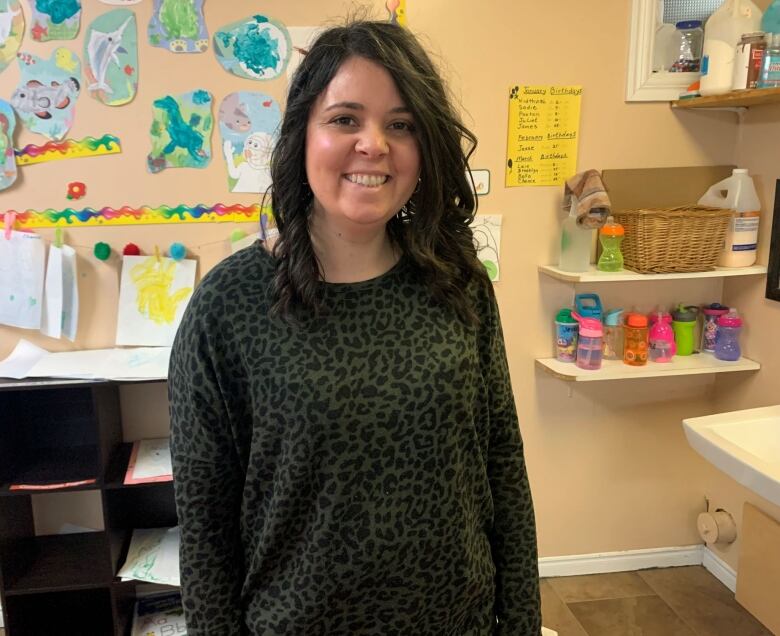 Melanie Cochrane with children's drawings on a bulletin board.