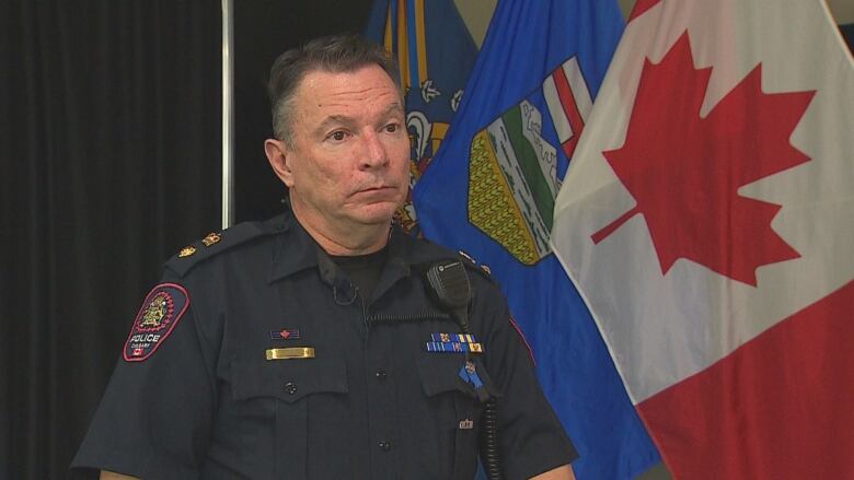 A police officer poses in front of an Alberta and Canada flag.