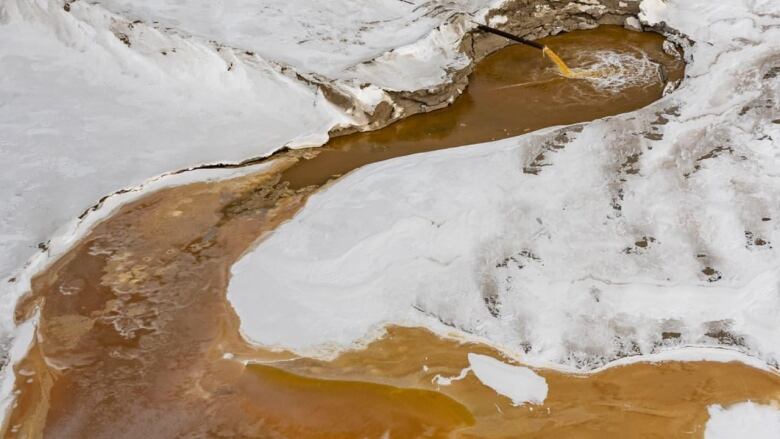 orange brown water on a snowy landscape.