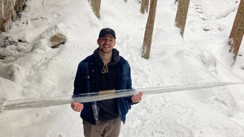 Mitchell Van der Ploeg is carrying a large icicle in this harms surrounded by snow on the Chief trail in Squamish