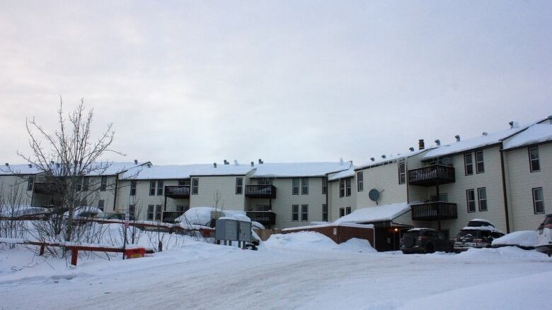 Low-slung ivory coloured building sprawling behind snowy parking lot.