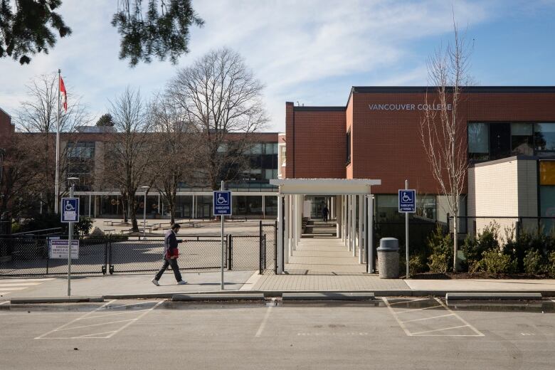 A brick school building and parking lot is pictured on a sunny day.