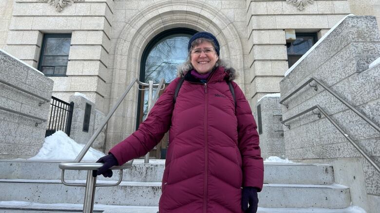 A woman is standing in front of an ornate tyndall stone building.