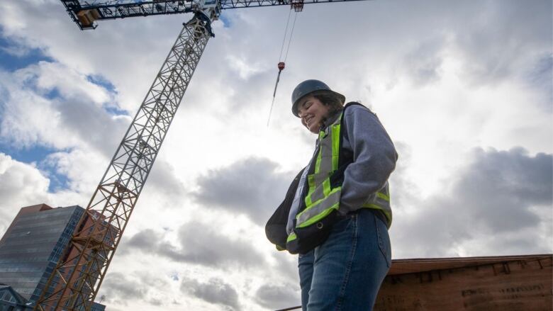 A crane operator stands silhouetted by the sky with a crane in the background.