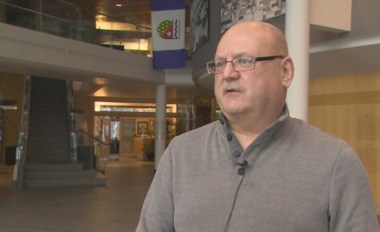 A close up of a man standing in the lobby of an institutional building.