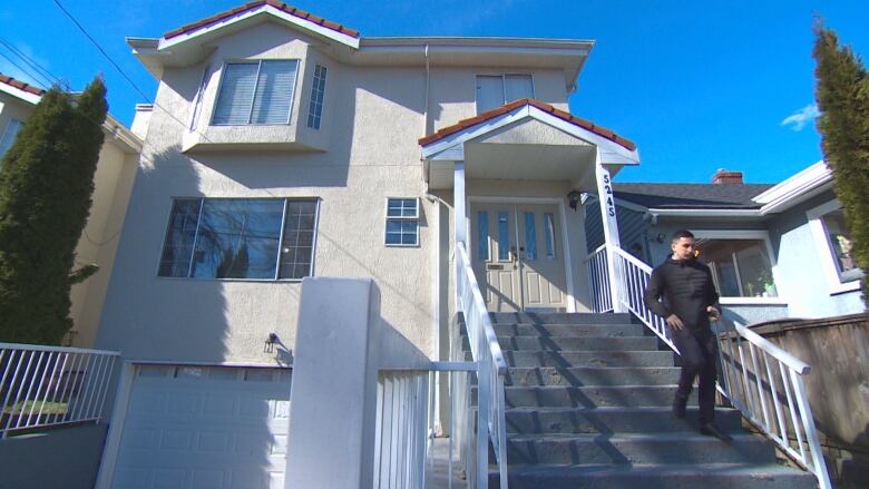 A person walks down the steps of a house.