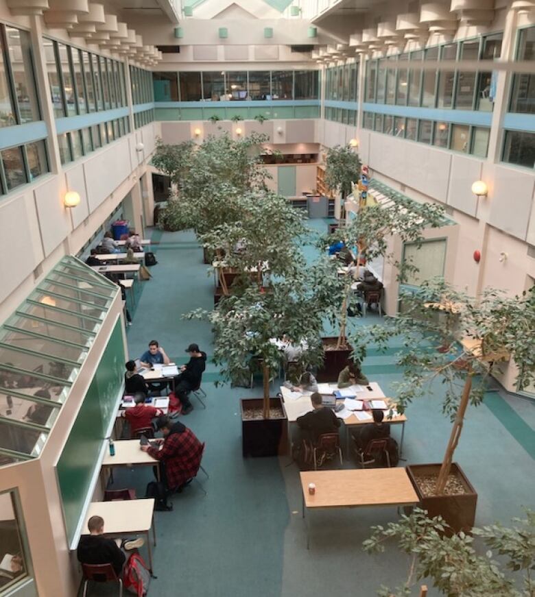 Students work at tables in an open room with high ceilings