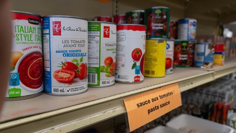 Cans of tomato sauce line the shelves at a food bank.