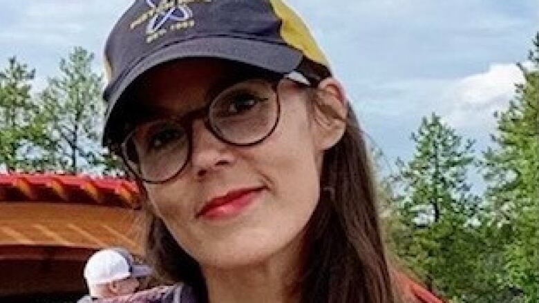 Smiling woman in ball cap, red lipstick.