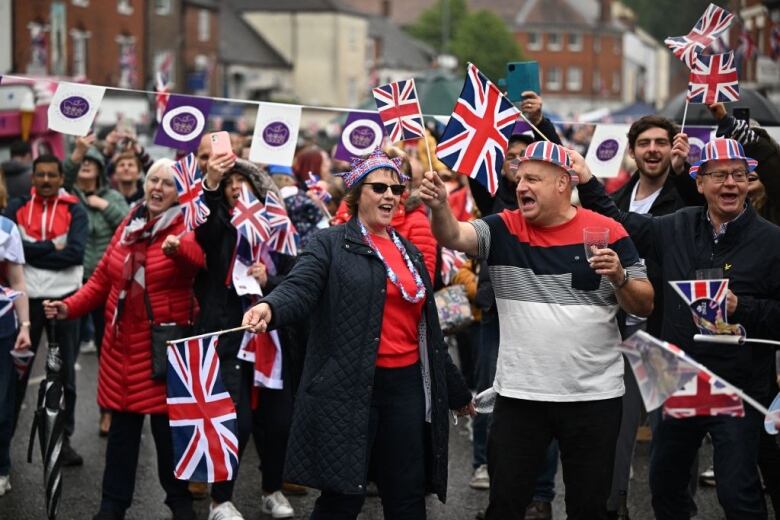 People wave flags and sing as they take part in a street party.