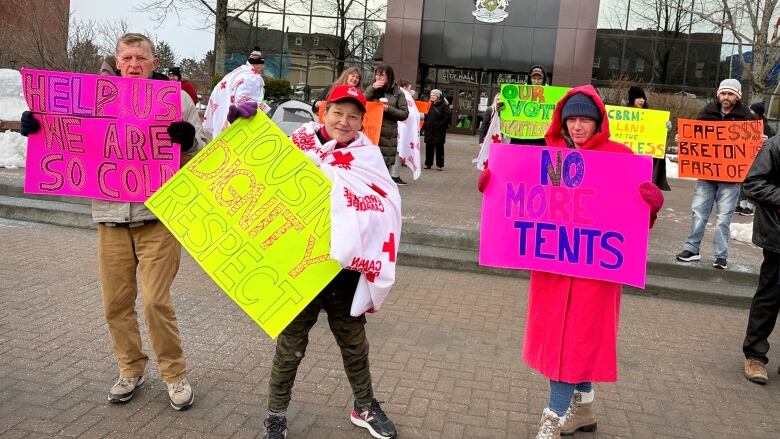 Protesters carrying signs set up in front of CBRM city hall.