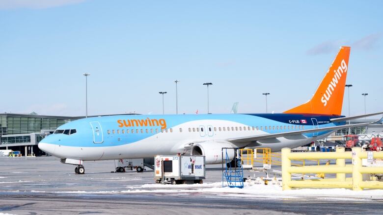 A Sunwing aircraft is seen parked on the tarmac of an airport. 