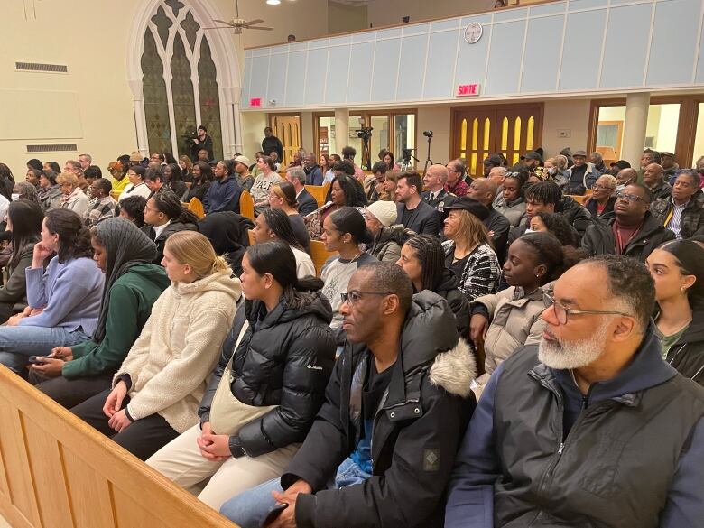 A large crowd of people sitting on church pews